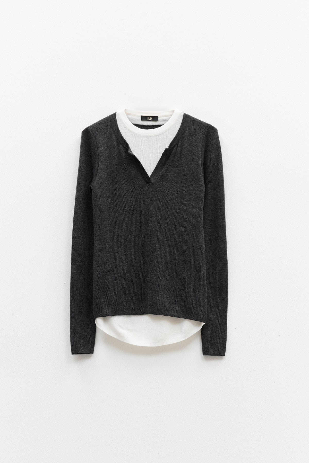 The ELEH - SWEATER WITH BUILT IN T-SHIRT features a charcoal gray sweater with a V-notch neckline layered over an attached white round-neck shirt, both displayed against a plain white background.