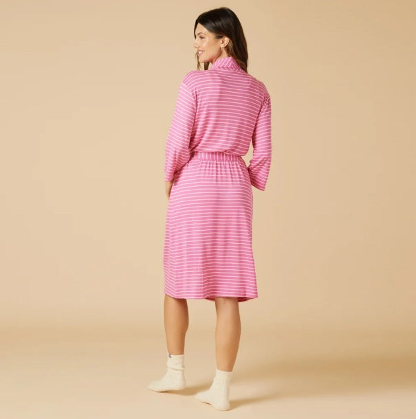 A woman wears a SOFTIES - DREAM SHAWL COLLAR ROBE IN FUSCHIA STRIPE over a matching tank top and drawstring shorts, offering spa-like luxury.