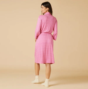 A woman wears a SOFTIES - DREAM SHAWL COLLAR ROBE IN FUSCHIA STRIPE over a matching tank top and drawstring shorts, offering spa-like luxury.