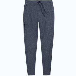 Close-up of a person wearing MACK WELDON Ace Sweatpants in True Navy Bird’s Eye with a tailored fit, drawstring waist, and pockets—one hand in the front pocket—paired with a dark blue shirt.