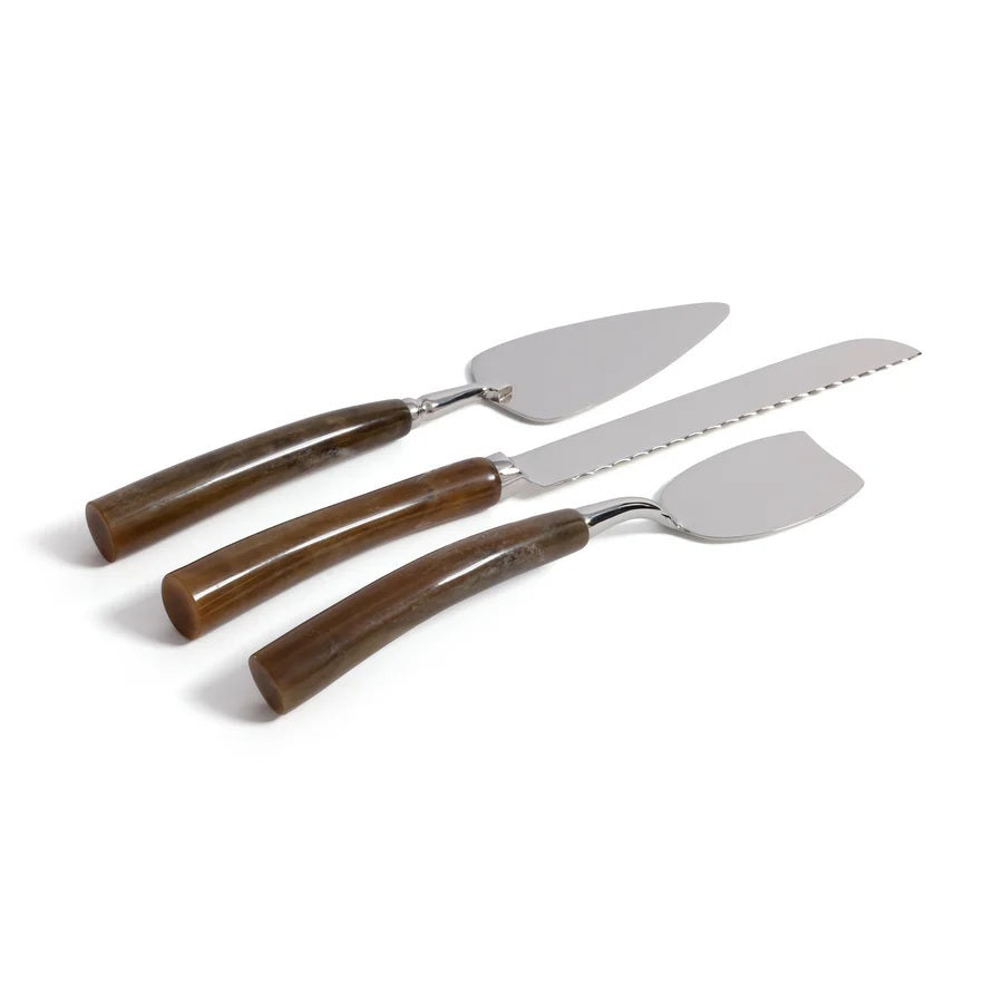 Three stainless steel utensils from the ZODAX GOURMET CHEESE KNIFE SET—a cake server, a serrated cake knife, and a pie server—feature brown curved handles and are arranged side by side on a white background. Perfect for an elegant cheese board presentation, these versatile tools showcase sleek design and impeccable craftsmanship, making them the ideal complement to any gourmet setting.