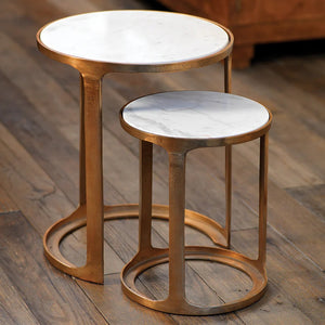 The ZODAX NIKKI Round Marble and Alloy Nesting Tables feature white marble tops and gold frames. Perfect for chic living rooms, the smaller table partially tucks under the larger one, offering style and space-saving versatility on any wooden floor.