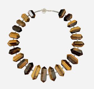 The ANN LIGHTFOOT - TIGER EYE DOUBLE POINTS RAS DU COU NECKLACE features striking brown and gold faceted tiger eye gemstones, symmetrically arranged and finished with a sterling silver clasp for an elegant look.
