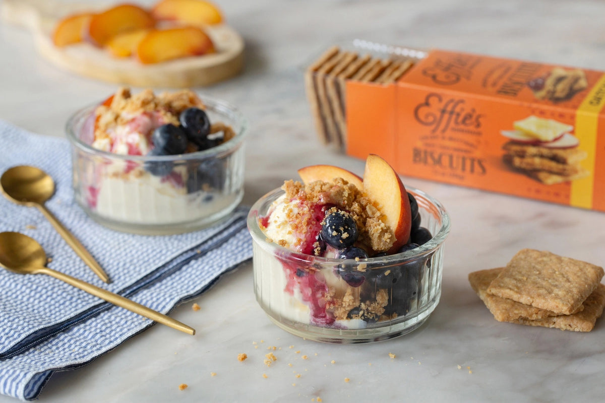 Front view of EFFIES HOMEMADE ORIGINAL OATCAKE BISCUIT box, orange with an image of stacked oatcakes topped with jam, and a small window displaying the buttery layers and toasted oats inside.