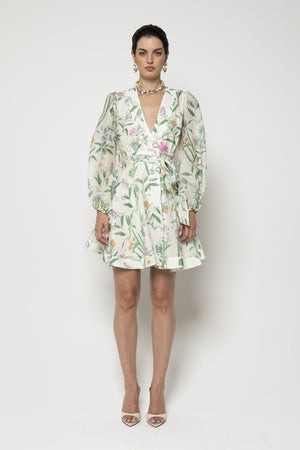 A close-up of the LAVI COUTURE - LIGEA FLORAL DRESS from LAVI highlights a vibrant botanical floral print with diverse flowers and green leaves on a black background. Bright oranges, pinks, blues, and greens add to the lively elegance of this exquisite Italian-made piece.