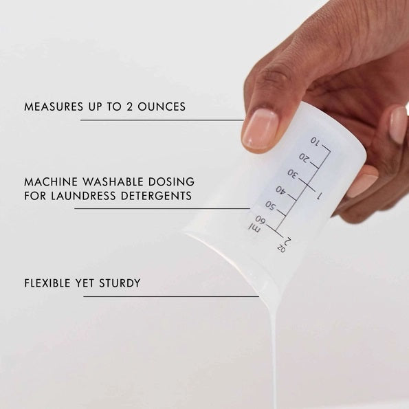 The LAUNDRESS - MEASURING CUP by THE LAUNDRESS is a white plastic measuring cup featuring ounce and milliliter markings on the side, making it ideal for accurately measuring THE LAUNDRESS detergents and other fabric care products.