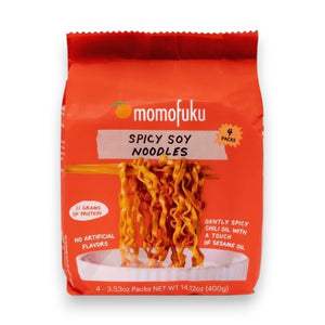A bright orange bag of MOMOFUKU - SPICY SOY NOODLES shows a bowl of air-dried noodles, notes five packs inside, no artificial ingredients, and a net weight of 16.75 oz (1.05 lb).