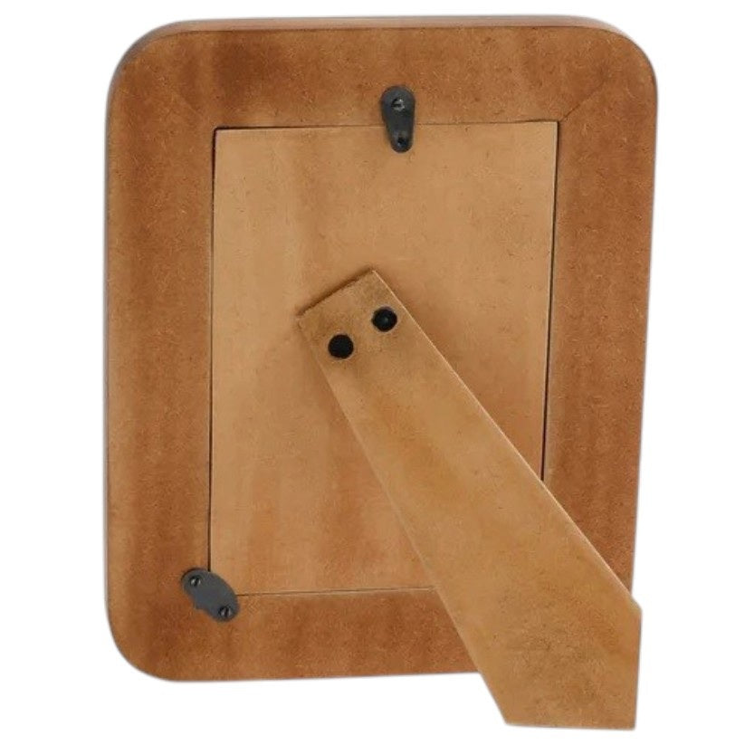 The ZODAX Black Resin Ribbed Photo Frame with Brass Accent (4x6) is shown from the back, featuring a rectangular support stand and two metal clasps securing the rear panel.