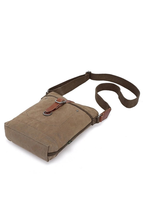 The TSD BRAND - FOREST ZIP CROSSBODY BAG IN OLIVE is a military-inspired khaki canvas bag with a front pocket, brown adjustable strap, decorative leather buckle, metal rivets, and textured shoulder strap for style and durability.