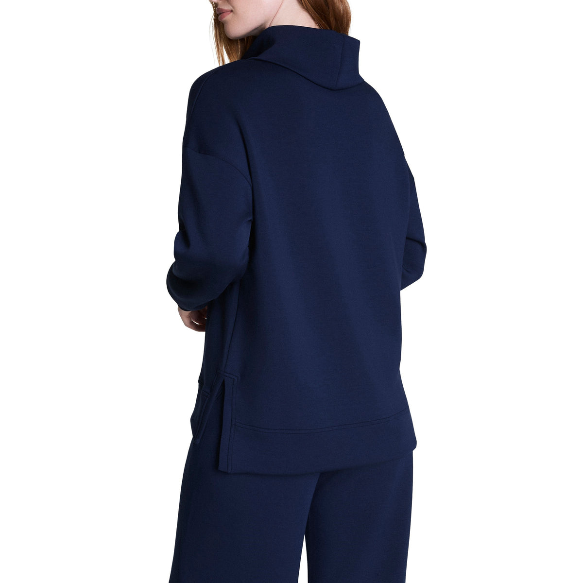 A woman in the SPANX AirEssentials Turtleneck Tunic in Timeless Navy displays a relaxed fit made with breathable spacer fabric for comfort.