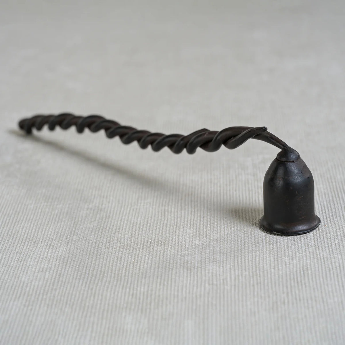 The ZODAX TWISTED WROUGHT IRON CANDLE SNUFFER features a black, spiral handle and a small, cup-shaped snuffer at one end, shown isolated on a white background.
