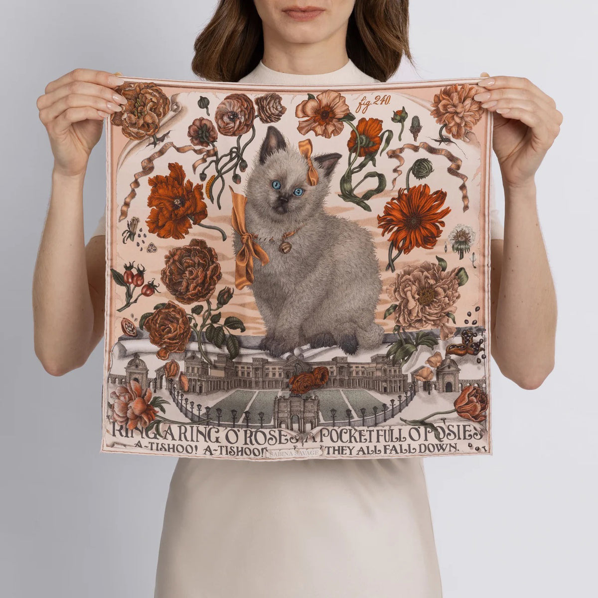 A fluffy gray kitten with a ribbon sits among vintage-style botanical illustrations on the 100% Silk Twill Sabina Savage - Ring a Ring O' Roses scarf, featuring an ornate banner and elegant flowers and ribbons.