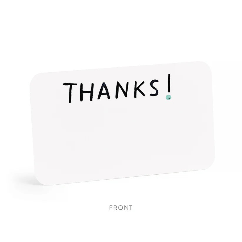 A clear plastic box contains E. Frances Paper - Thanks Little Notes, each decorated with "THANKS!" on the cover. These charming cards showcase a subtle watercolor design, encouraging generous use for any occasion.