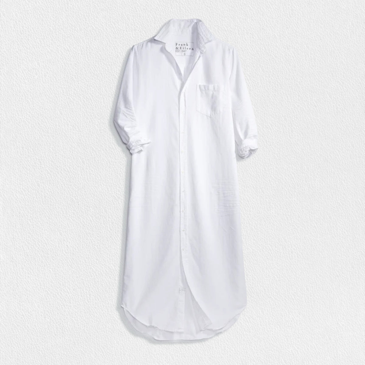 The FRANK &amp; EILEEN Rory Maxi Shirtdress in Famous Denim is a full-length button-up dress featuring a collar, rolled-up sleeves to mid-length, and a single chest pocket. Its sleek, minimalist design embodies that California chic look against a plain white textured background.