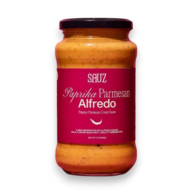 A clear glass jar of SAUZ - PAPRIKA PARMESAN ALFREDO sauce from SAUZ, made in Italy with clean ingredients. The creamy orange sauce is visible through the packaging, while a red label highlights the flavor and product details.
