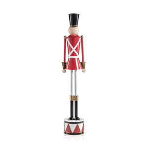The ZODAX ALLOY FESTIVE DECORATIVE SOLDIER - TALL features a classic nutcracker style with alloy accents, a red coat, white straps, gold details, and stands upright on a small drum base for a modern festive touch.