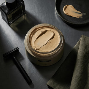 An open, round container of HYGIENELAB - STYLING CLAY displays the smooth, light gray clay inside with a swirled surface. This styling clay from HYGIENELAB provides a medium-strong hold and a natural matte finish.