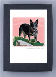 Introducing the PAPER RUSSELLS - AUSTRALIAN CATTLE DOG NOTE CARDS by PAPER RUSSELLS: Featuring a charming illustration of an Australian Cattle Dog standing on grass with a pink sky in the background. The dog displays a black and brown coat, alert ears, and a joyful, open-mouthed expression. Made in the USA and crafted on recycled paper, each card includes &quot;Australian Cattle Dog&quot; text beneath the image.