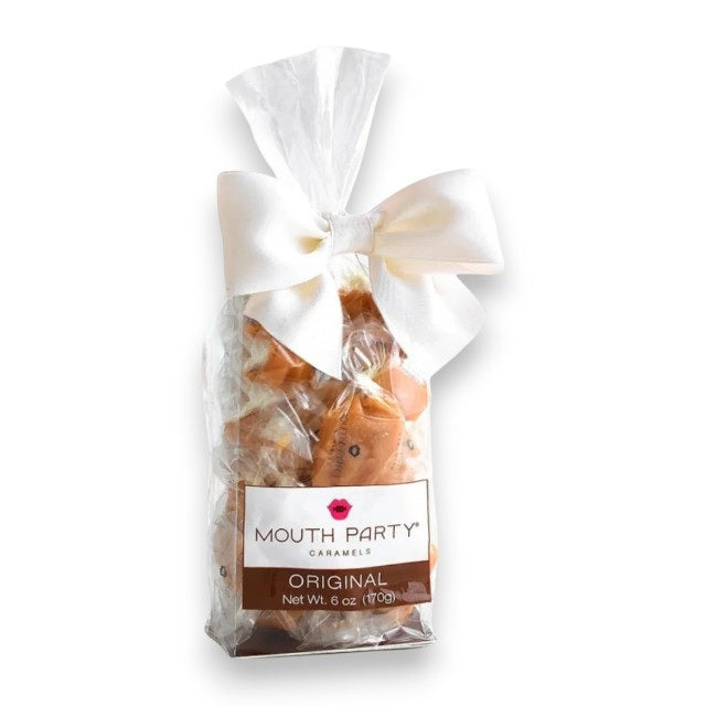 A clear bag of MOUTH PARTY - ORIGINAL CARAMEL BAG from MOUTH PARTY, net weight 6 oz, is tied at the top with a large white bow. Each creamy caramel is made from a cherished family recipe.