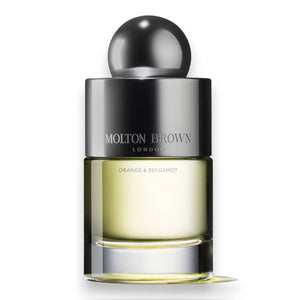A bottle of MOLTON BROWN - ORANGE AND BERGAMOT EAU DE TOILETTE, with Sevillian orange and neroli notes, features a round black cap and clear glass revealing the light yellow fragrance inside.
