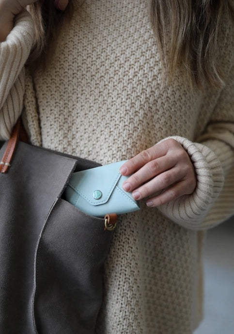 The E. FRANCES PAPER E. FRANNIE PACK, SEAGLASS is a mint green wallet with a snap closure, embossed with "E. FRANCES," ideal for holding Little Notes—perfect as a gift and shown against a white background.