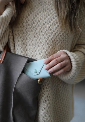 The E. FRANCES PAPER E. FRANNIE PACK, SEAGLASS is a mint green wallet with a snap closure, embossed with "E. FRANCES," ideal for holding Little Notes—perfect as a gift and shown against a white background.