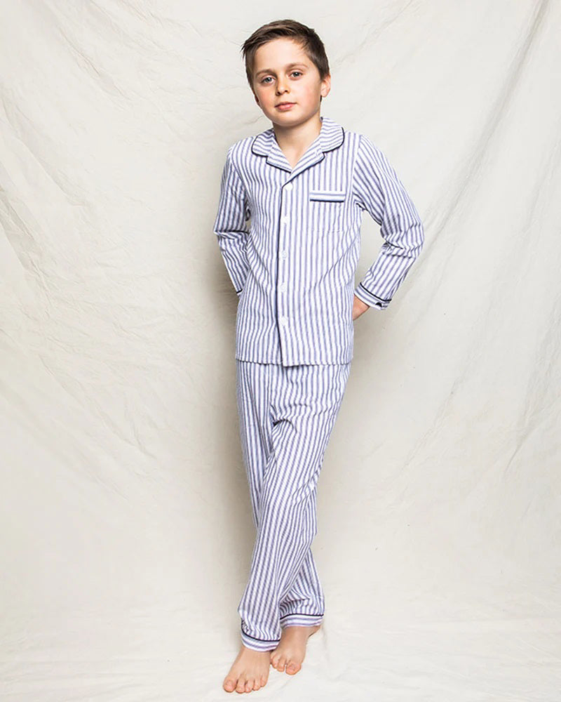 The PETITE PLUME FEARRINGTON LIFESTYLE COLLECTION - CHILDREN&#39;S TWILL NAVY FRENCH TICKING PAJAMA SET is a delightful option for kids, featuring long sleeves and pants with chic vertical white and gray stripes. This set is crafted from yarn-dyed cotton, boasting a top with a collar, full button-down front, and a single chest pocket adorned with matching fabric piping along the cuffs and pocket opening.