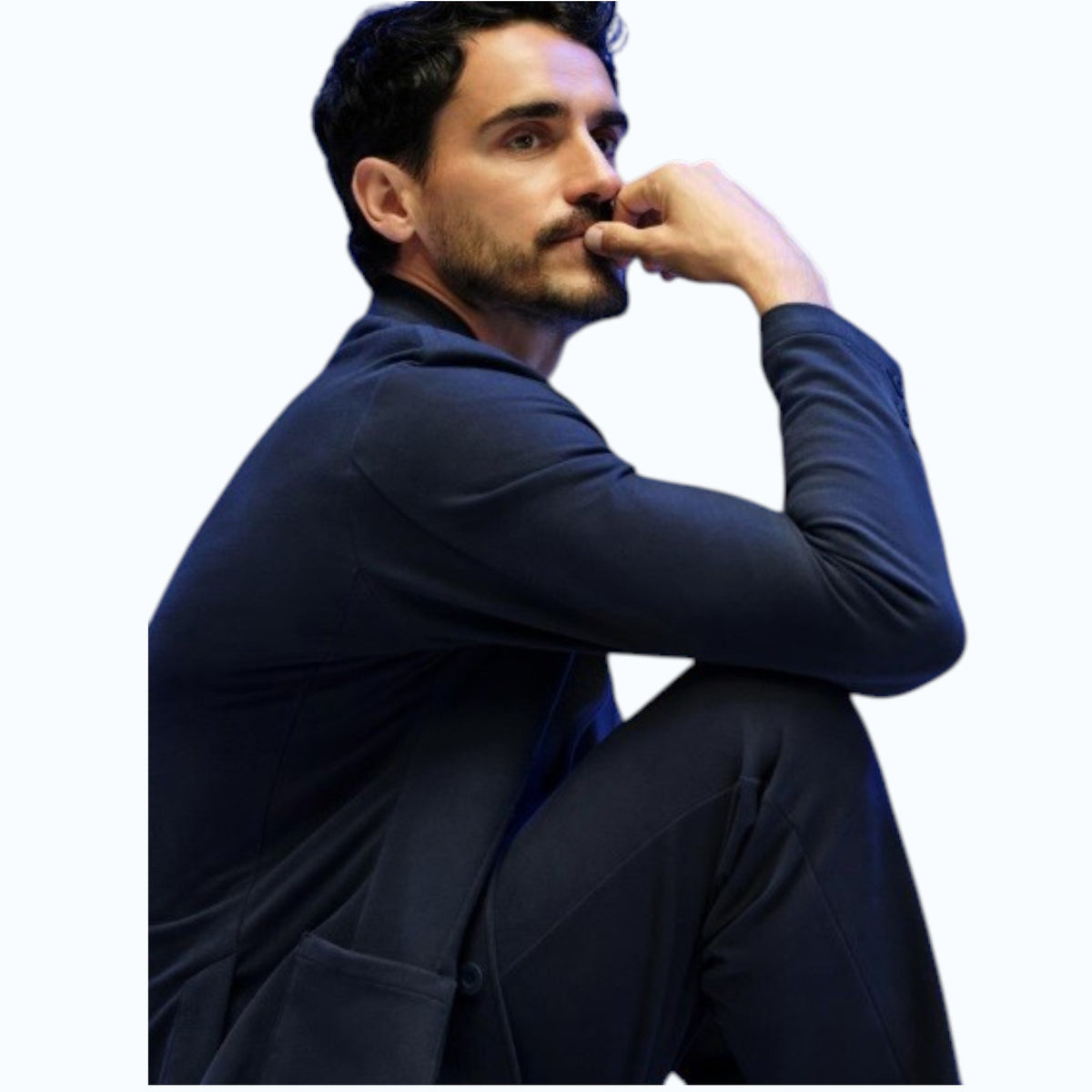A man with short dark hair and a trimmed beard wears the MACK WELDON Ace Blazer in Total Eclipse over a white t-shirt, looking slightly to the side while buttoning his blazer against a plain light background.