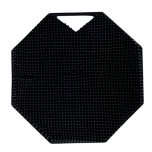 The SILICONE BODY AND EXFOLIATION BRUSH IN ONYX from SMILE BOUTIQUES features a black, octagonal silicone design with a textured, raised dot surface and a small triangular handle cutout at the top—perfect for use as a reusable shower brush or exfoliating body scrubber.