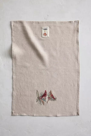 A CORAL & TUSK CHRISTMAS CARDINALS LINEN TEA TOWEL made of embroidered natural flax fiber featuring two cardinals perched on pine branches with berries.