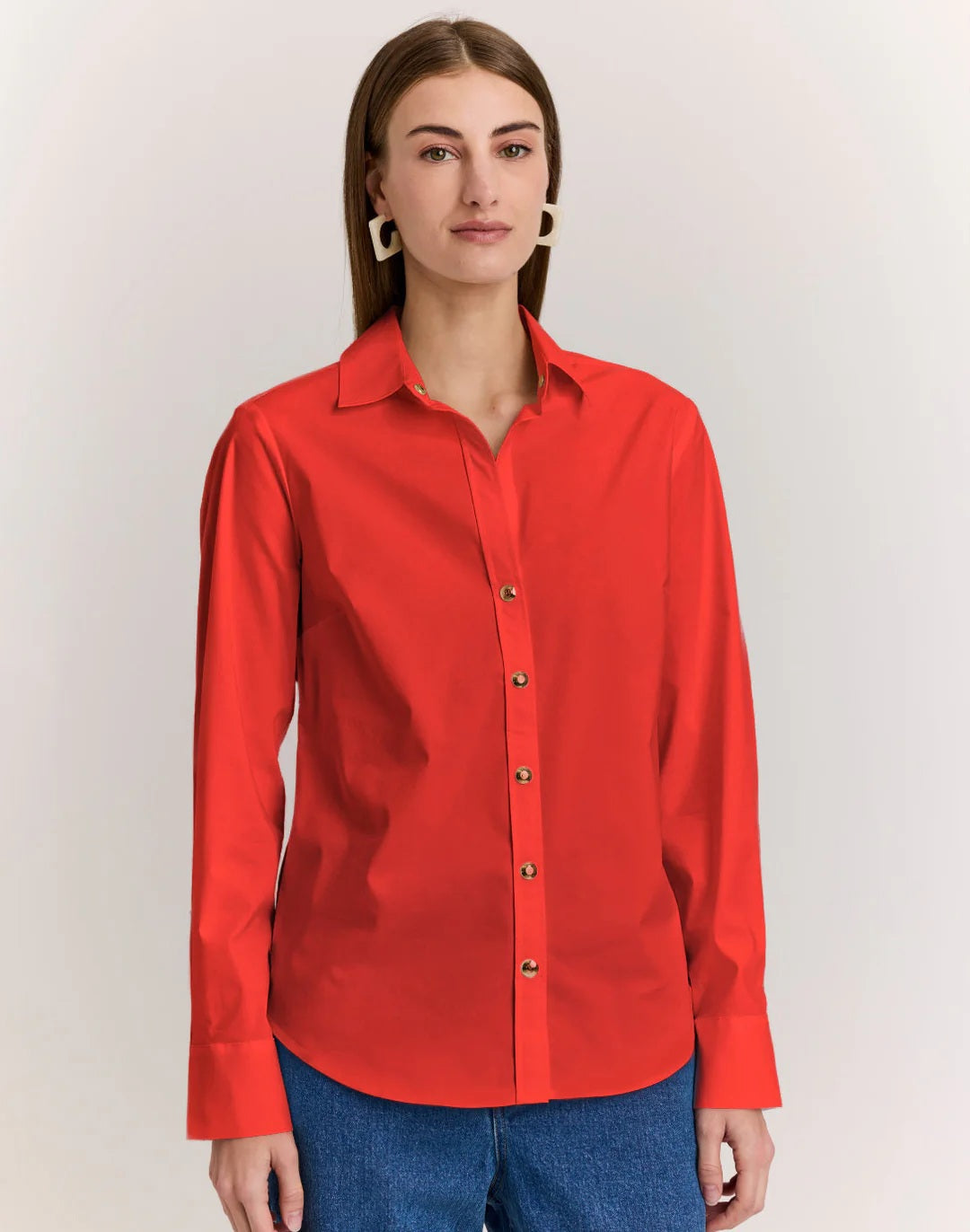 A person with straight brown hair wears the HINSON WU CLARICE Long Sleeve Shirt in Poppy and blue jeans, standing against a plain light background.