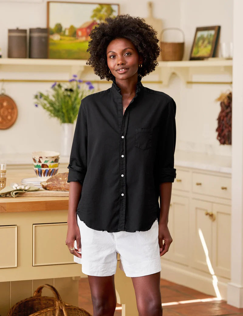 The FRANK &amp; EILEEN Ruffle Eileen Ruffle Collar Button Up Shirt in Famous Denim Blackout features long sleeves, white buttons, a single chest pocket, and a ruffled collar, shown laid flat against a white background.