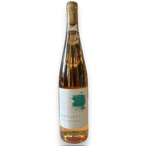 A tall, clear bottle of GALLICA ESTATE ROSÉ 2024 by WINE: JOHNSON BROS./OXFORD ST. gleams golden-pink with a white label and teal splash, topped by cork and gold foil, highlighting the wine’s refined style.