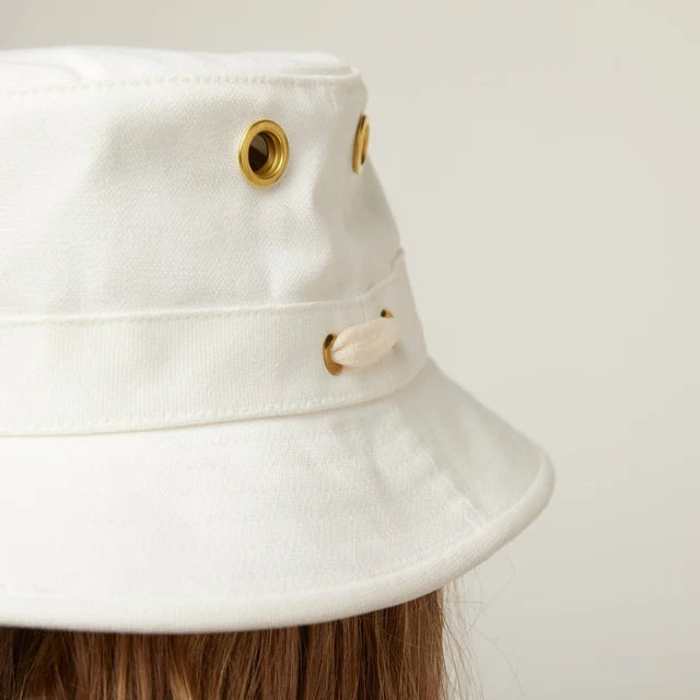 A person wearing the TILLEY - ICONIC T1 BUCKET HAT IN WHITE and a white shirt is shown from the back against a light gray background—a stylish, breathable cotton hat by TILLEY, perfect for sun protection.