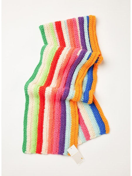 The MERSEA - BRIGHTSIDE SCARF by MERSEA is a colorful knit scarf with horizontal stripes in orange, yellow, green, blue, pink, red, and white. Made from soft acrylic yarn for warmth and comfort; displayed on a white background with a small tag attached.