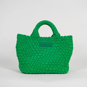 A woman with long brown hair, in a sleeveless cream knit top and blue jeans, holds a PARKER AND HYDE - MINI WOVEN TOTE BAG. The hand-woven tote by PARKER & HYDE features a subtle checkered pattern with light blue accents.