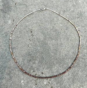 The ANN LIGHTFOOT - Mookite Ombre Ras du Cou Necklace features small, round brown and pink beads with a sterling silver clasp, shown in a circular shape on a white background.