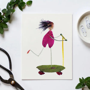 The PETAL PEOPLE PRESS - SCOOT birthday card by PETAL PEOPLE PRESS features a charming figure made from leaves and petals riding a plant-based scooter, ideal for nature lovers. Card is shown on a white surface with leaves, scissors, and paperclips.