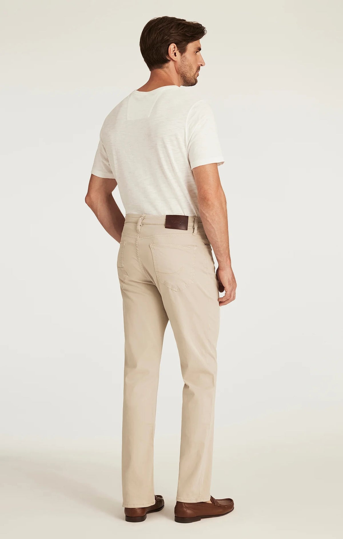 A man with light brown hair and a beard wears a tan blazer, brown sweater, white collared shirt, 34 HERITAGE - CHARISMA RELAXED STRAIGHT LEG PANT IN DAWN TWILL by 34 HERITAGE, and brown shoes against a plain white background.
