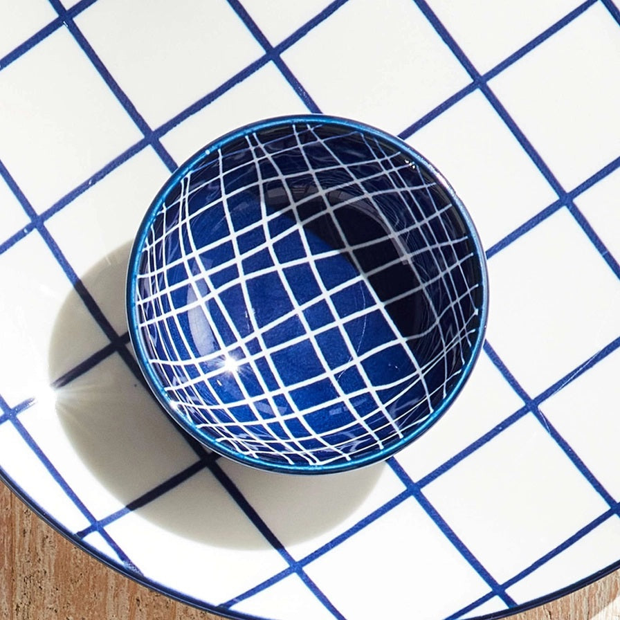 The NAPA HOME AND GARDEN Blue and White Stria Dip Bowl features a blue grid pattern and sits on a matching large white plate, both adding modern style to your table. Dishwasher safe, this tableware is perfect for entertaining.
