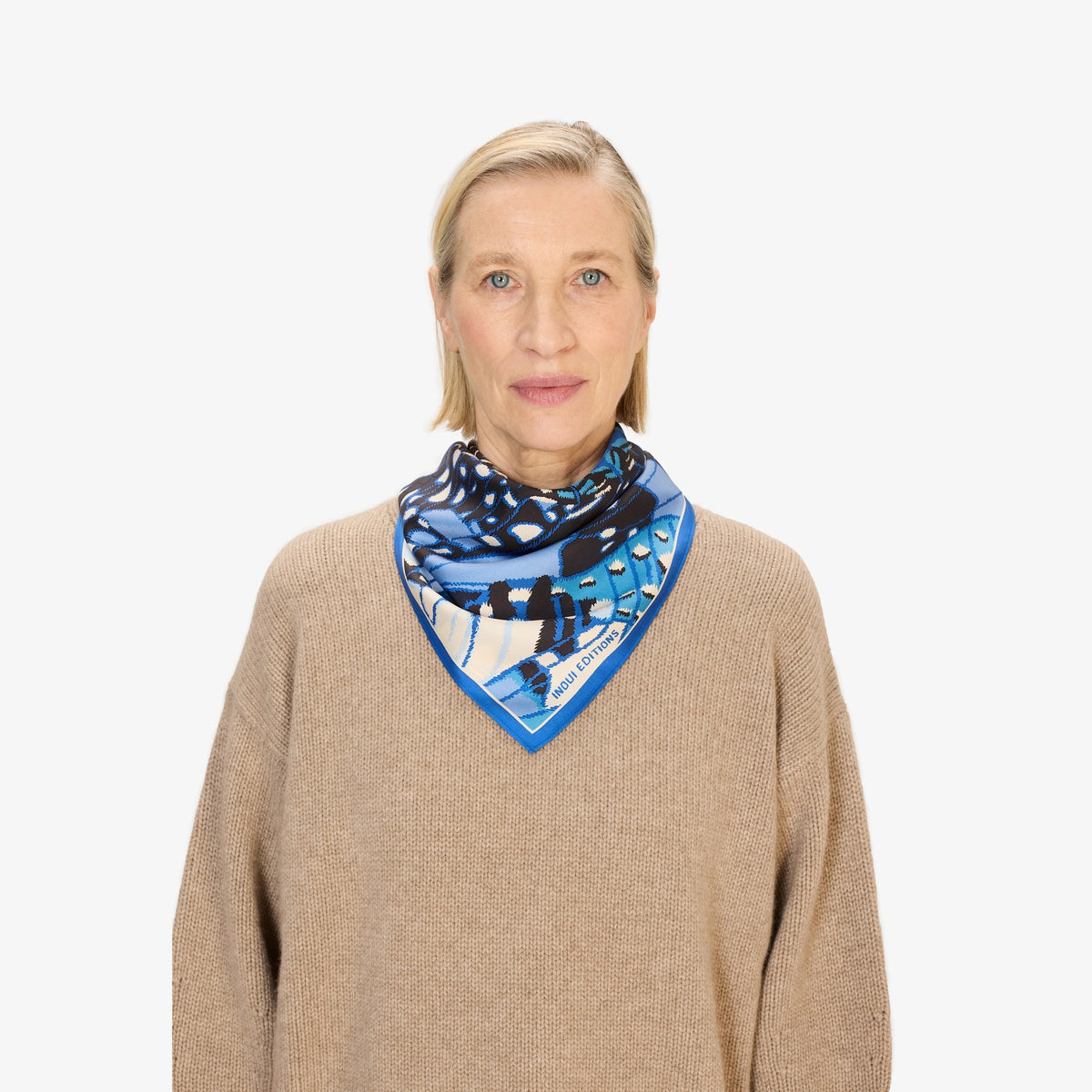 A close-up of the INOUI EDITIONS PAPILLON silk scarf in blue, featuring a smooth, shiny texture and abstract butterfly-inspired pattern in blue, black, and cream—a versatile accessory crafted in India by INOUI.