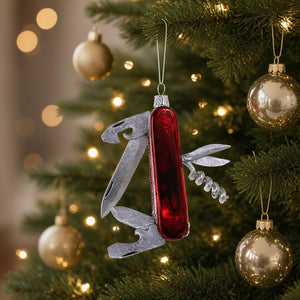 A 3.5-inch GLASS SWISS ARMY KNIFE ORNAMENT by Cody Foster, shaped like a multi-tool pocket knife with a red handle and silver folded blades.
