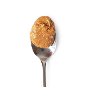 A metal spoon holds BIG SPOON ROASTERS - WAG BUTTER PUMPKIN SPICE against a plain white background—an excellent healthy dog treat from BIG SPOON ROASTERS.