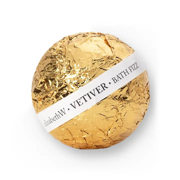 A spherical, nourishing fizz ball wrapped in crinkled gold foil with a white label encircling it, displaying the text "E Wightman &amp; Co Vetiver Fizz Ball.