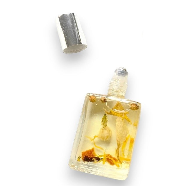 A small rectangular glass bottle labeled “MADISON AND GREEN - RISE & REFRESH MORNING AROMATHERAPY BODY OIL MINI” from MADISON GREEN, featuring a silver cap and visible botanical pieces suspended in the lightweight, plant-based oil.