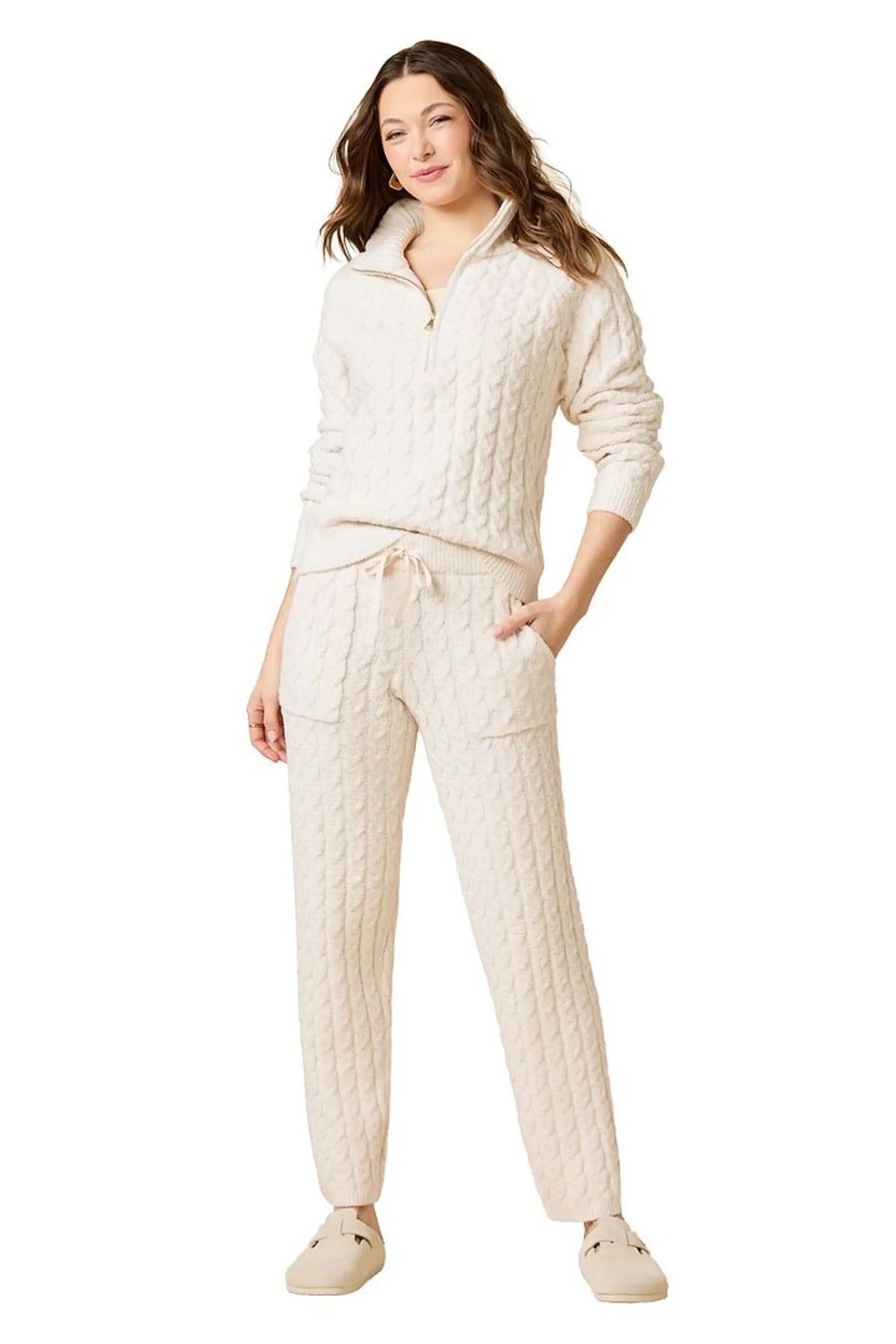 A woman wearing a marshmallow-soft, cream-colored SOFTIES - CABLE KNIT MARSHMALLOW ½ ZIP WITH TAPERED PANT SET, featuring a half-zip pullover and matching pants with a drawstring waist.