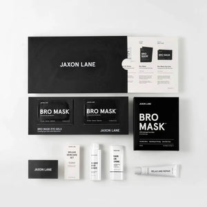 The JAXON LANE - DELUXE SKINCARE SET FOR MEN by JAXON LANE includes the BRO MASK, Rain or Shine sunscreen, Shake and Wake, and two large black boxes, all displayed neatly on a white surface.
