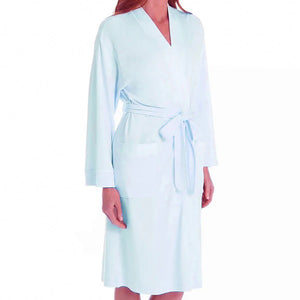 A person wearing the P. JAMAS - BUTTERKNIT SHORT ROBE by FASHIONVIEWS, made of silky light blue fabric with a tied belt. The robe features long sleeves, two pockets near the waist, and a design reminiscent of a kimono style. The individual is standing against a plain white background, with their head not visible.