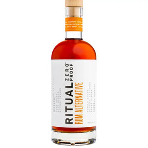 A bottle of RITUAL ZERO PROOF- RUM ALTERNATIVE by RITUAL ZERO PROOF, featuring a tan cap, amber liquid, and a white label with bold black and orange text describing this non-alcoholic rum alternative.