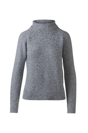 A woman stands against a white background wearing the KINROSS CASHMERE Marled Garter Funnel Cotton Sweater in Navy and white pants. With her hair pulled back, she rests one hand near her chin and looks calmly at the camera.